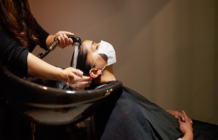 Woman wearing a face mask getting her hair washed in a salon